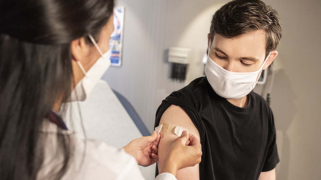 Man receiving Band-Aid on arm from nurse following vaccination