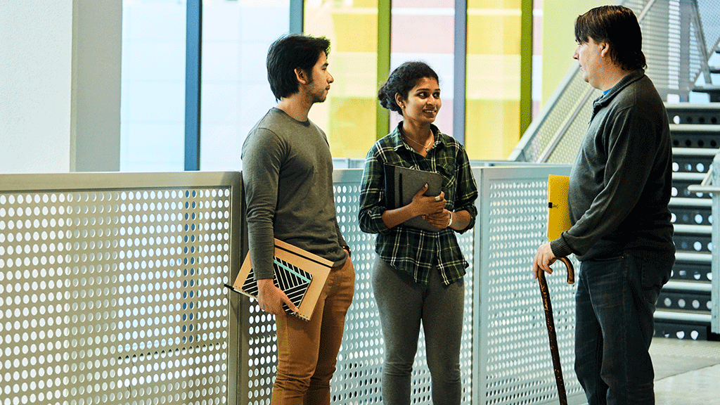 Two male and one female student chatting on campus