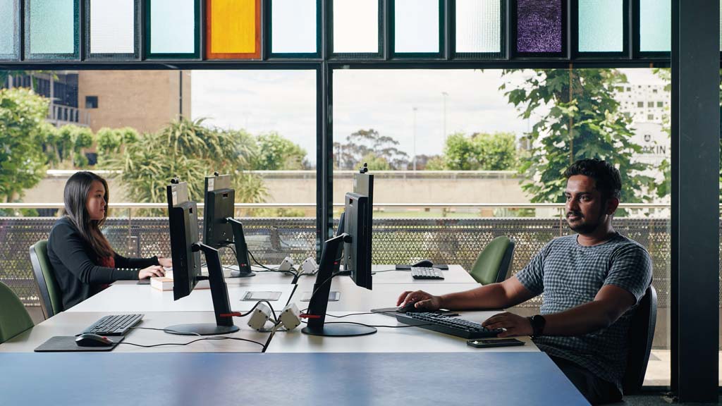 Two students working on computers across from each other in Waurn Ponds library
