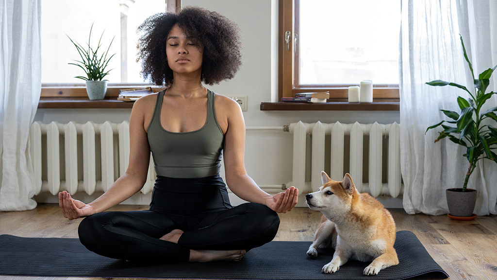 woman meditating with her dog at home
