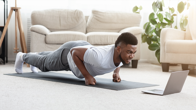 young male planking at home taking online pilates class