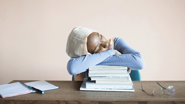 Exhausted student slumped on pile of books