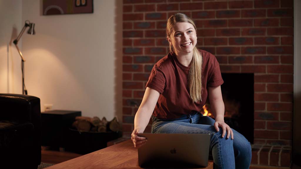 Student smiling as she works on laptop from home