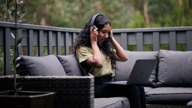 Student wearing headphones and using laptop outside