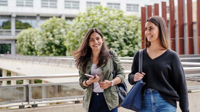 Student smiling as she walks with a friend outside at Waurn Ponds Campus