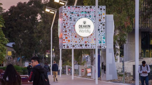 Students walking past Deakin Cube on Morgan's Walk at Burwood Campus in the early evening