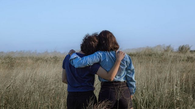 Back view of two young women with arms around one another