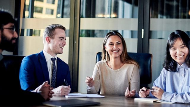 Four people around a table in a CBD office smiling