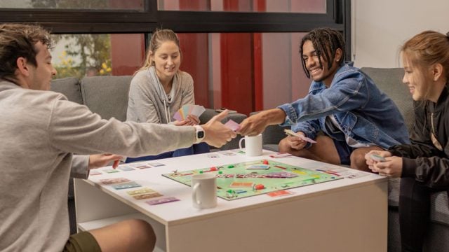 A group of people sitting around a table playing the board game Monopoly