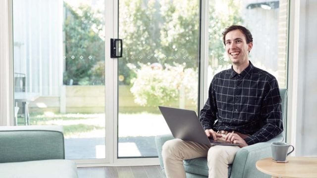 Student smiling as he works on laptop from home