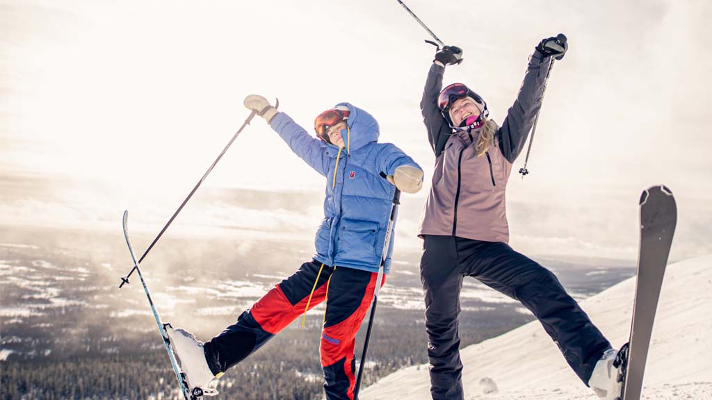 Two women in ski gear posing on a mountain
