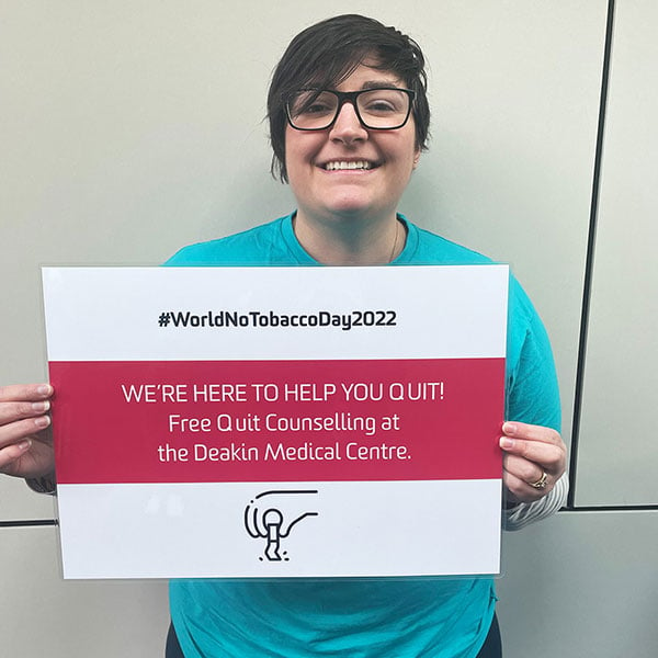 Deakin Wellbeing Ambassador holding sign that says: '#WorldNoTobaccoDay2022. We're here to help you quit! Free Quit counselling at the Deakin Medical Centre.'