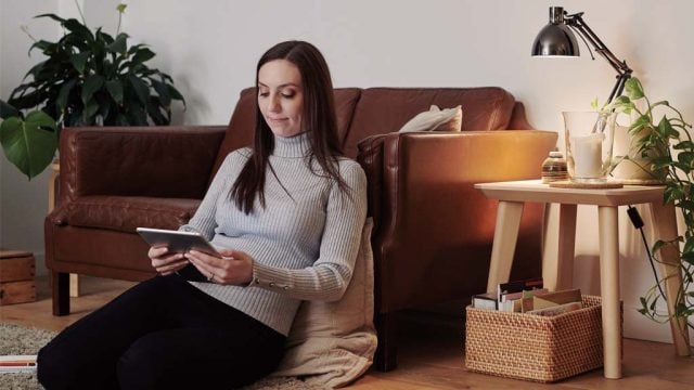 Woman looking at tablet while sitting on lounge room floor