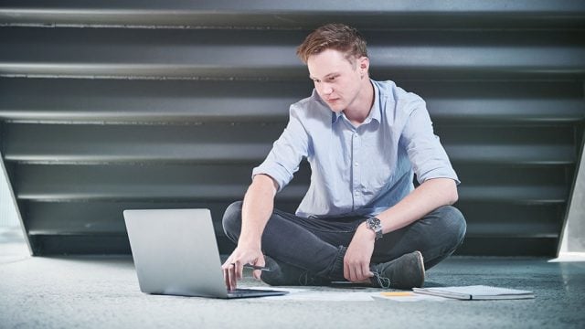 Male student sitting on floor with laptop
