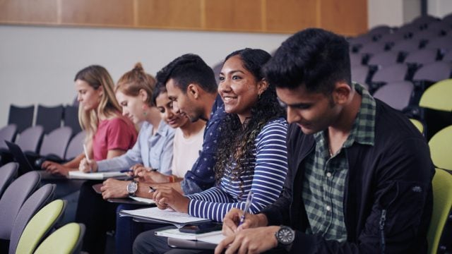 Student smiling among friends in lecture theatre