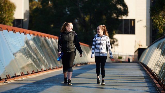 Two students walking over footbridge at Burwood Campus