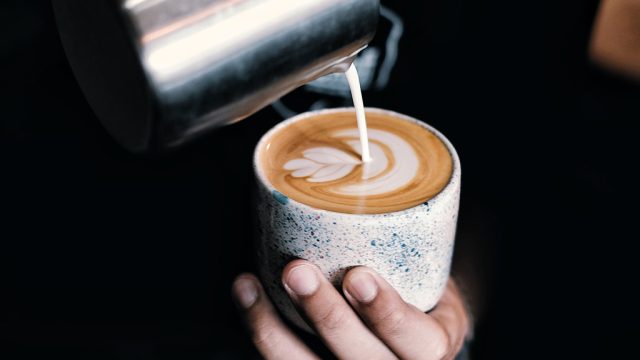 Close up of barista pouring milk into coffee