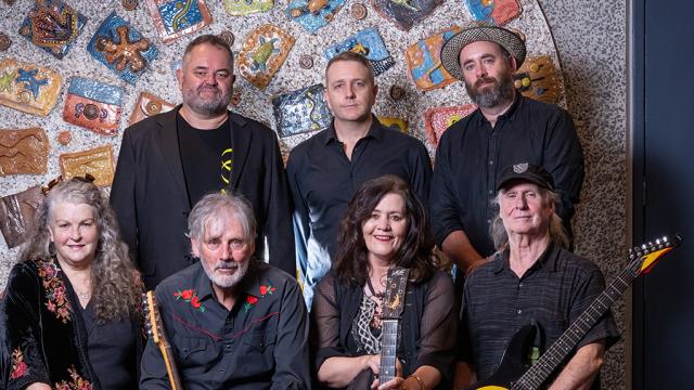 members of the band Goanna standing against a mural