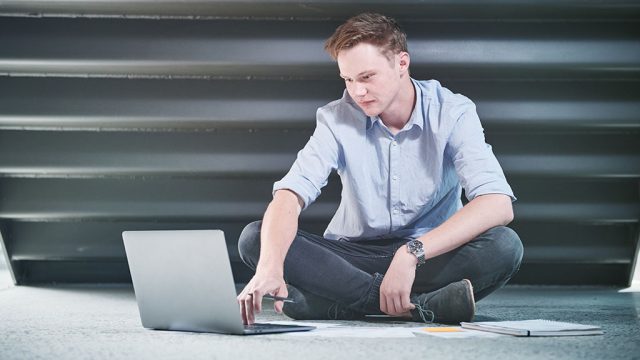 Male student sitting on floor with laptop