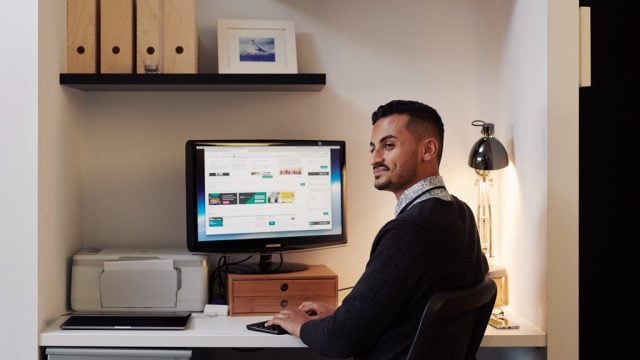 Student smiling as he sits at desk at home