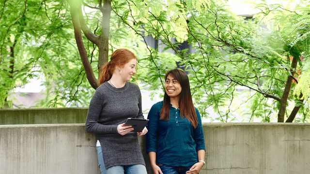 Students smile while talking outside on campus