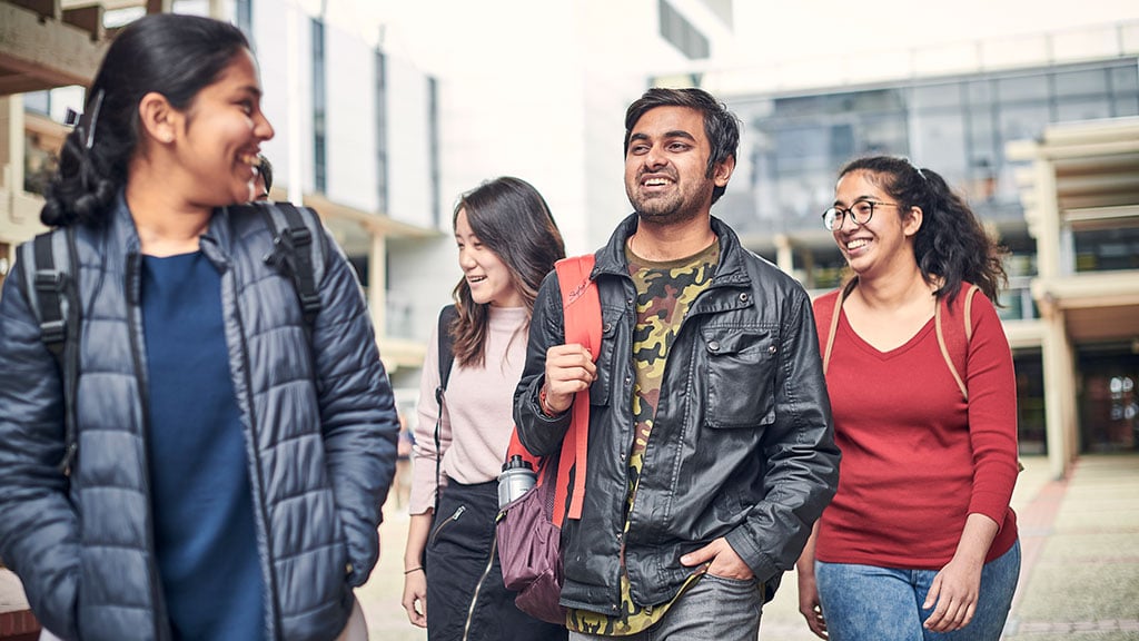 Group of four international students walking on campus
