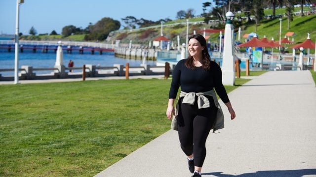 Student smiling as she walks along Eastern Beach in Geelong