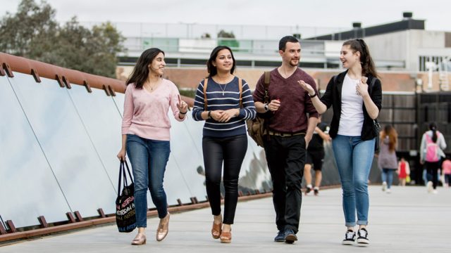 Four students walking across footbridge at Burwood Campus