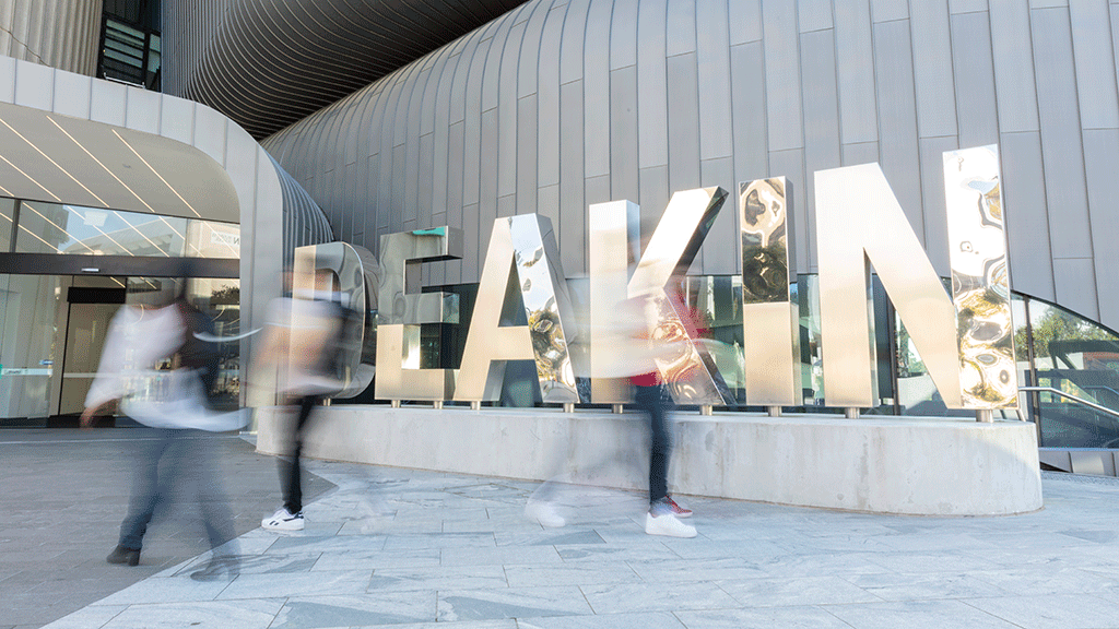 Blurred images of people walking past Deakin sign