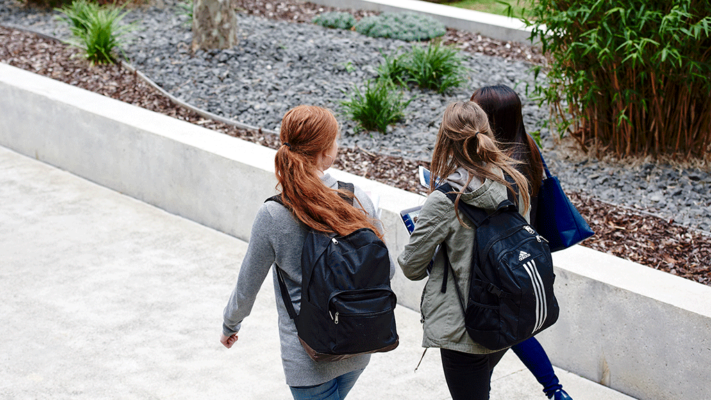Three students walking across campus