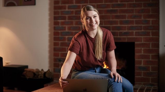 Student smiling as she looks at laptop