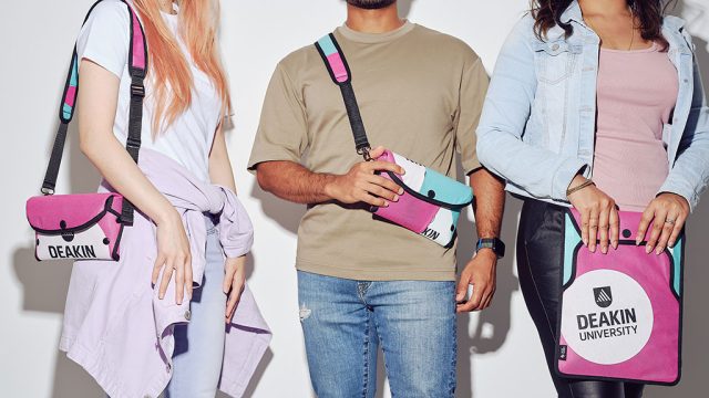 Cropped shot of three students holding Deakin-branded bags