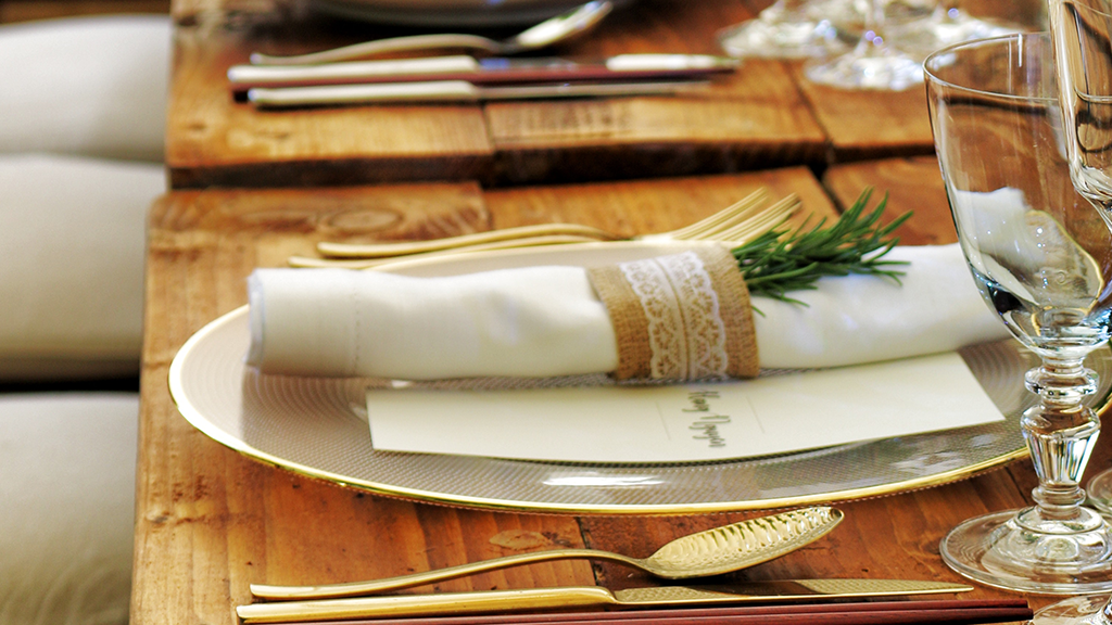 restaurant table dressed with crockery, cutlery, glasses, napkin and menu.