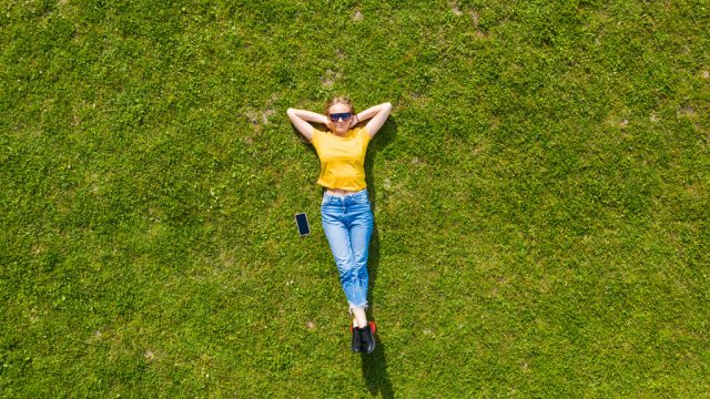Woman relaxing on grass looking up at sky
