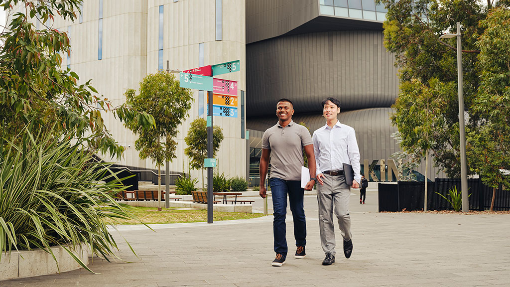 Two male students walking across campus