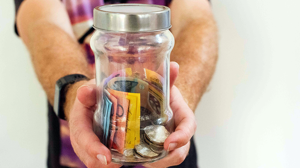 person holding a jar full of Australian money