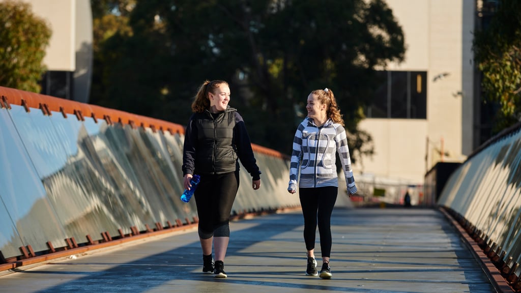 Two students chatting as they walk across bridge at Burwood