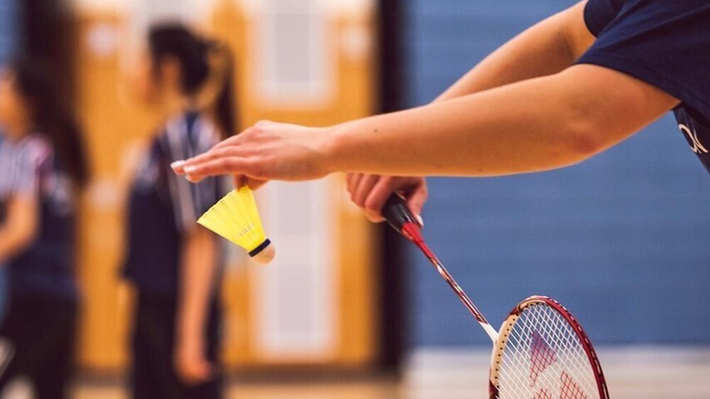 Person holding badminton racquet and shuttlecock