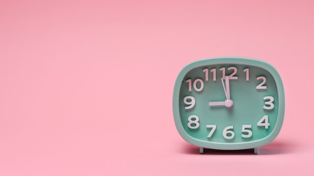 Green clock against pink background