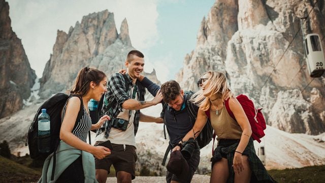 Four travellers laughing in front of mountain range