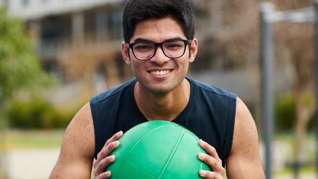 Student smiling as he exercises with medicine ball
