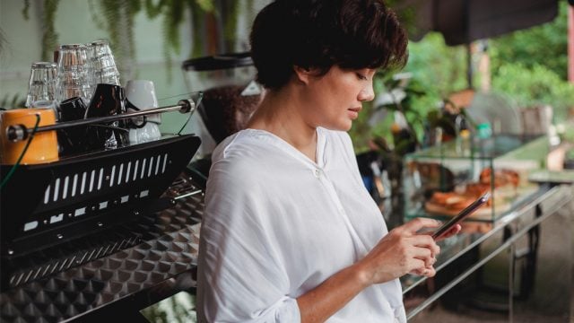 Woman browsing mobile phone in cafe