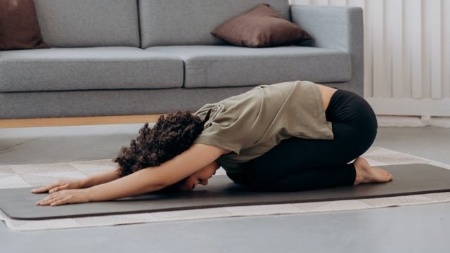Woman doing a yoga pose on a mat at home