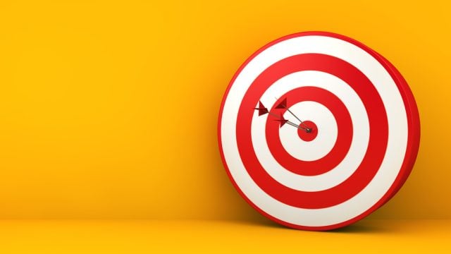 Arrows in middle of red and white target board against yellow background