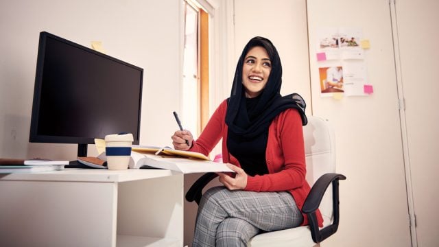 Student smiling as she studies at desk at home