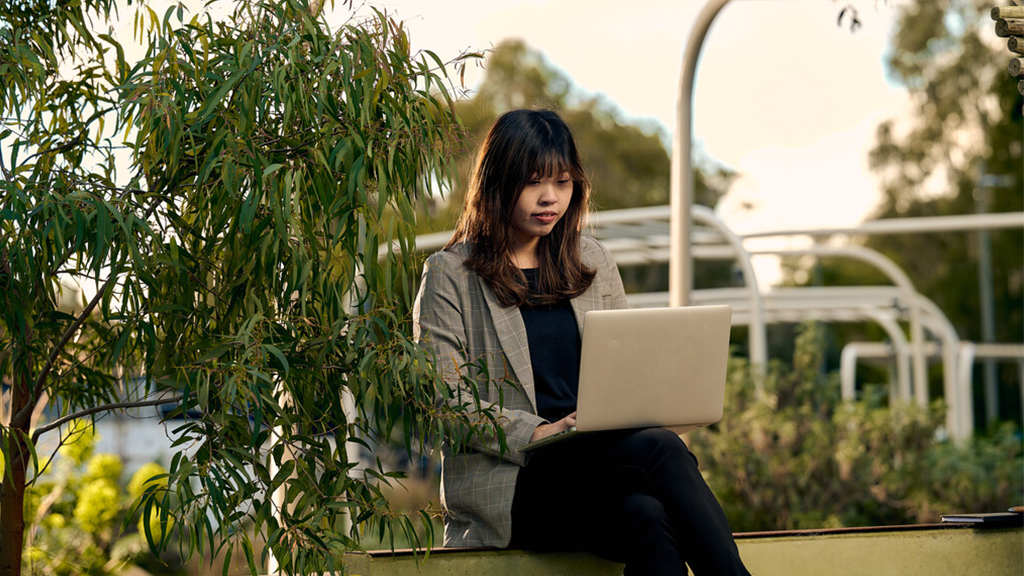A student sitting on campus accessing eduroam on their laptop.