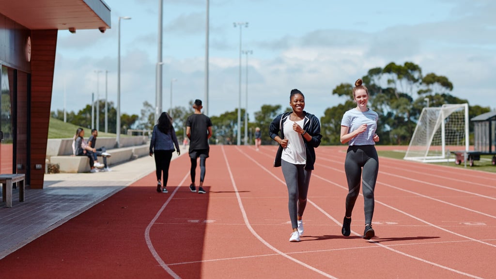 Two students walking together on the track at the Elite Sports Precinct at Waurn Ponds Campus