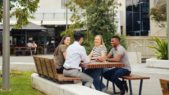 Four students sitting around an outdoors table at Burwood Campus