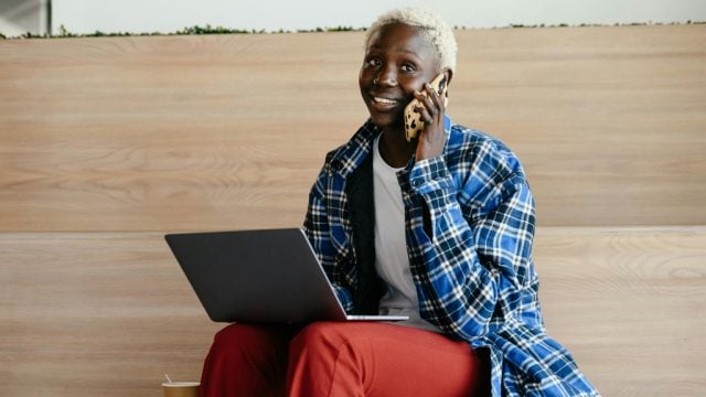 Woman talking on phone while working on laptop