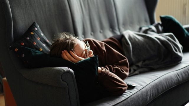 Woman laying on couch with TV remote